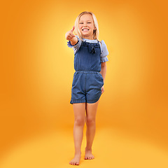 Image showing Happy, portrait of child and thumbs up in studio for support, like emoji or yes approval. Excited girl kid on orange background or space for hand gesture, barefoot or sign for agreement or thank you