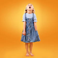 Image showing Fashion, wow and girl child in studio for news, omg or coming soon promotion on orange background. Looking up, surprise and kid shocked by choice, sale or discount, announcement or prize giveaway