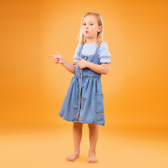 Image showing Girl, portrait and child with finger gun in studio for advertising announcement or promotion. Young kid on orange background for pointing or hand sign for direction, attention or fashion mockup space