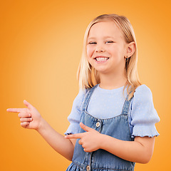 Image showing Happy, portrait and child with finger gun in studio for advertising announcement or promotion. Young girl kid on orange background for pointing or hand sign for direction, attention or excited smile