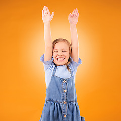 Image showing Excited, celebration and girl child with arms up in studio for success, winner or happy on orange background. Yes, news and kid with hands, smile and celebrating achievement, victory or announcement