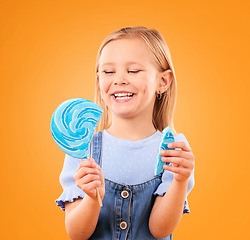 Image showing Lollipop, candy and a child laughing in studio for sweet tooth, color spiral or sugar for energy. Face of happy girl kid on orange background for funny snack or thinking of dessert or unhealthy food
