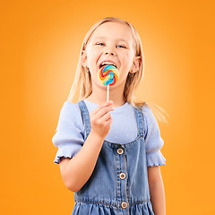 Image showing Lollipop, girl child and portrait of candy in hand, eating and studio for sweets, birthday party or carnival. Sugar, kid and lick spiral snack for dessert, hunger or meal on orange background