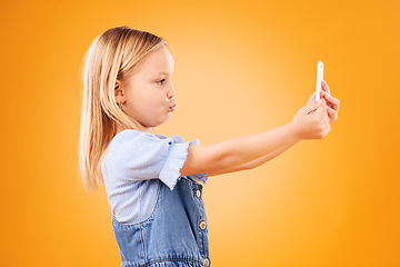 Image showing Phone, selfie or profile of kid in studio with confidence or mockup space in photograph memory. Pout, orange background or young girl child taking picture online on a social media app on internet