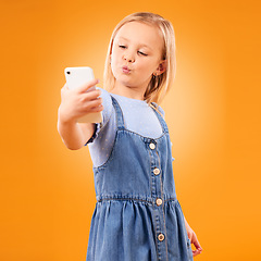 Image showing Kiss, selfie or child in studio with confidence or mockup space for photograph memory on web. Fashion, orange background or young girl taking pictures online on a social media app to post on internet