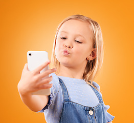 Image showing Kiss, selfie or face of kid in studio with confidence or mockup space in photograph memory. Web, orange background or young girl taking fun pictures online on a social media app to post on internet