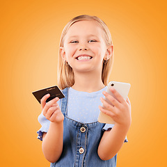 Image showing Portrait, child and credit card with phone in studio for online shopping order, digital payment and fintech on orange background. Happy girl kid, smartphone and buy mobile games, sales and savings