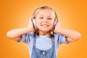 Image showing Headphones, portrait or child streaming music to relax with freedom in studio on orange background. Face, smile or happy girl listening to a fun radio song, sound or audio on an online subscription