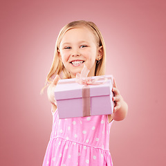 Image showing Studio, giving present portrait of a child for birthday, holiday or happy celebration. Excited girl kid on a pink background with ribbon on gift box for surprise, giveaway prize or celebrate kindness