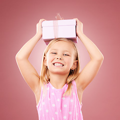 Image showing Gift, present and child with box on head for birthday, holiday or happy celebration. Portrait of excited girl on a pink background for surprise, giveaway prize or celebrate kindness for charity