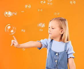 Image showing Young girl child, pop bubbles and game, playing and fun with youth isolated on orange background. Liquid soap, development with kid from Australia in studio, playful and toys with childhood