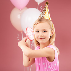 Image showing Girl kid, birthday party and balloons in studio portrait, lollipop and hat for celebration, event and red background. Female child, face and candy with gift, present and decoration to celebrate