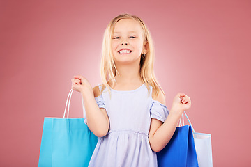 Image showing Portrait, happy and girl kid with shopping bag, customer and purchase with fashion isolated on pink background. Retail, smile and young child with gift, luxury and buying, discount and sale in studio