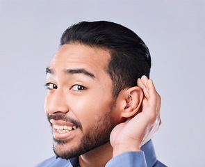 Image showing Deaf, portrait and asian man with hand on cochlear in studio for speak up, listen or communication on grey background. Hearing aid, face and Japanese guy with a disability, emoji and sign for implant