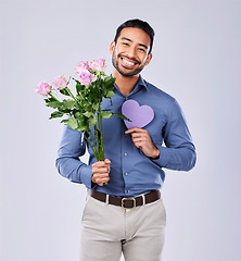 Image showing Purple heart, portrait and asian man with roses in studio for thank you, gift or care on grey background. Paper, frame and Japanese male model with flower, bouquet or offer, love or valentines day