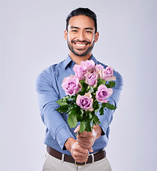 Image showing Roses, portrait and happy man in studio with thank you, present or offer on grey background space. Face, flowers and Japanese male model with floral, bouquet or gesture of kindness, love or romance