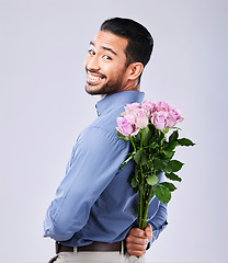 Image showing Flowers, portrait and man in studio with surprise roses in celebration of valentines day or romance on grey background. Face, smile and male person with floral gift for love, care or romantic gesture