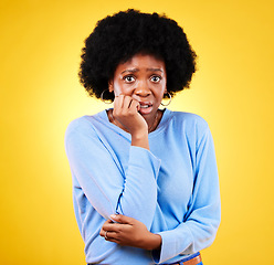 Image showing Biting nails, anxiety and a scared woman in studio for fear, mental health or nervous behaviour. Portrait of African person on yellow background worried, stress or panic for phobia, terror or horror