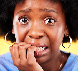 Image showing Anxiety, biting nails and a woman scared in studio with fear, mental health or nervous behaviour. Face portrait of African person on yellow background worried, stress or panic for phobia or horror