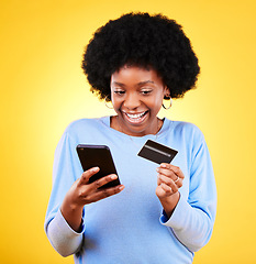 Image showing Happy black woman, phone and credit card in online shopping against a yellow studio background. Excited African female person with afro smile on mobile smartphone app in ecommerce, payment or banking