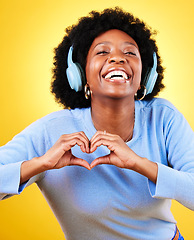 Image showing Portrait, heart hands and headphones of woman in studio for sign, kindness or thank you on yellow background. Happy african model, finger shape or icon of hope, love or emoji while listening to music