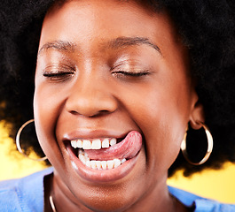 Image showing Tongue out, comic and closeup of black woman on a yellow background for happiness or crazy. Smile, face and an African girl or model with a silly or funny expression with comedy or goofy personality