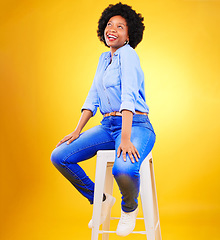 Image showing Black woman, smile and thinking on a chair in studio, yellow background or natural happiness with casual fashion and style. African, gen z or model relax with ideas for creative, mockup or space