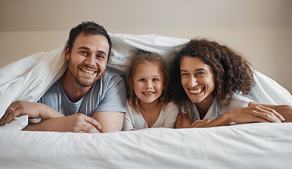 Image showing Smile, love and portrait of family in bed for bonding, relaxing and resting together with blanket. Happy, excited and young girl child laying with her mother and father in the bedroom of modern home.