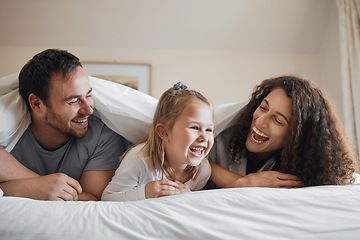 Image showing Laugh, happy and family in bed together bonding with comic, comedy or funny joke together. Smile, love and young girl child relaxing and having fun with her mother and father in the bedroom at home.
