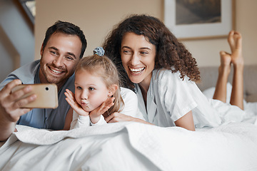 Image showing Selfie, happy and family on a bed together for bonding on a weekend morning at modern home. Smile, goofy and girl child taking a picture with her mother and father in the bedroom for memory at house.