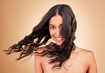 Image showing Portrait, woman and curly hair in wind on studio background for shine, beauty and keratin shampoo. Happy indian model, hairstyle and waves in breeze for aesthetic texture, growth and salon cosmetics