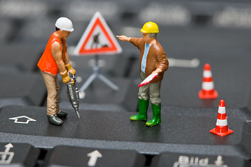 Image showing Miniature figures working on a computer keyboard.