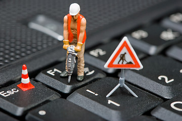 Image showing Miniature figures working on a computer keyboard.