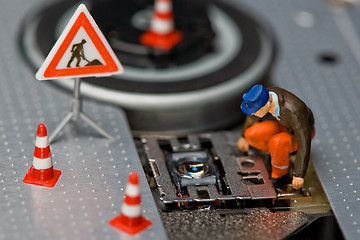 Image showing Miniature figures working on a DVD drive.