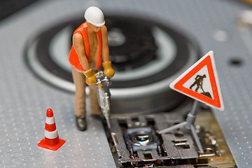 Image showing Miniature figures working on a DVD drive.