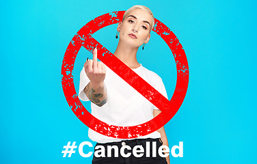 Image showing Portrait, rude and cancel culture with a woman on a blue background in studio to reject or deny an icon. Social media, hashtag and censorship with a rebel girl showing a hand gesture in protest