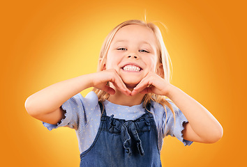 Image showing Happy, smile and portrait of child on orange background with happiness, joy and excited in studio. Fashion, childhood and hands on face of girl in fun or trendy outfit, young style and summer clothes