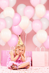 Image showing Depression, sad birthday and portrait of girl on pink background for party, celebration and event in studio. Upset, emotion and unhappy, lonely and disappointed child with balloons, presents or gifts