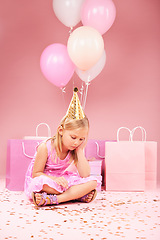Image showing Depression, sad birthday and girl on pink background for party, celebration and festive event in studio. Upset, emotion and unhappy, lonely and young child on floor with balloons, presents and gifts
