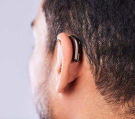 Image showing Ear, deaf and hearing aid closeup in studio on a gray background for sound, audio or communication. Technology, listening and a man with a disability closeup for implant or medical innovation