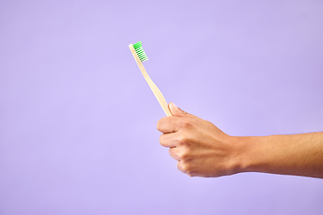 Image showing Dental, teeth whitening and hand with toothbrush in studio for oral care, wellness and hygiene on purple background. Mouth, cleaning and person show bamboo tool for fresh breath, tooth or gum health