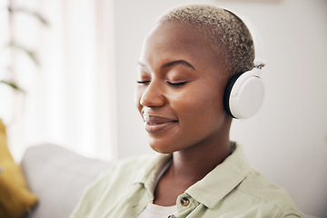 Image showing Black woman, listening and meditation podcast on headphones in home, living room or peace on sofa in lounge. Music, tech and happiness on face of person with zen, mindset and wellness in apartment