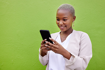 Image showing Black woman, typing and phone for communication by a wall or green background with internet. African person with a smartphone reading social media message, networking and mobile app chat space