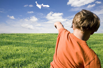 Image showing young boy flying a paper plane