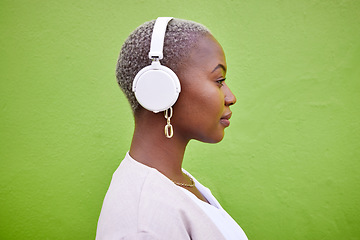 Image showing Music headphones, profile and black woman listening on green wall background mockup space. Radio, serious and African person streaming podcast, hearing audio and sound of jazz media on technology.