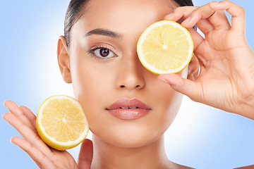 Image showing Woman, portrait and lemon on eyes in studio for vitamin c cosmetics, eco friendly beauty or detox diet. Face of model, healthy skincare or citrus fruits for sustainable dermatology on blue background