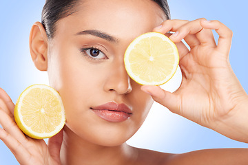 Image showing Lemon, portrait and beauty of woman in studio for vitamin c cosmetics, natural diet and detox. Face of model, healthy skincare and citrus fruits on eyes for sustainable dermatology on blue background