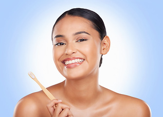 Image showing Portrait, woman and brushing teeth in studio for dental care, beauty or healthy smile on blue background. Happy model, bamboo toothbrush and cleaning mouth for oral hygiene, mint breath or gingivitis