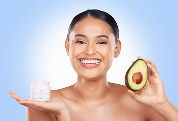 Image showing Woman, cream and avocado with natural beauty, vegan product and sustainable skincare on blue background. Portrait, smile and green fruit, lotion and eco friendly skincare with glow in a studio