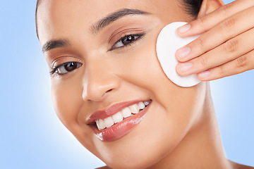 Image showing Woman, cotton pad and remove makeup, beauty and skincare with portrait on blue background. Smile, hygiene and grooming, cleaning face and product with cosmetics, skincare and wellness in studio